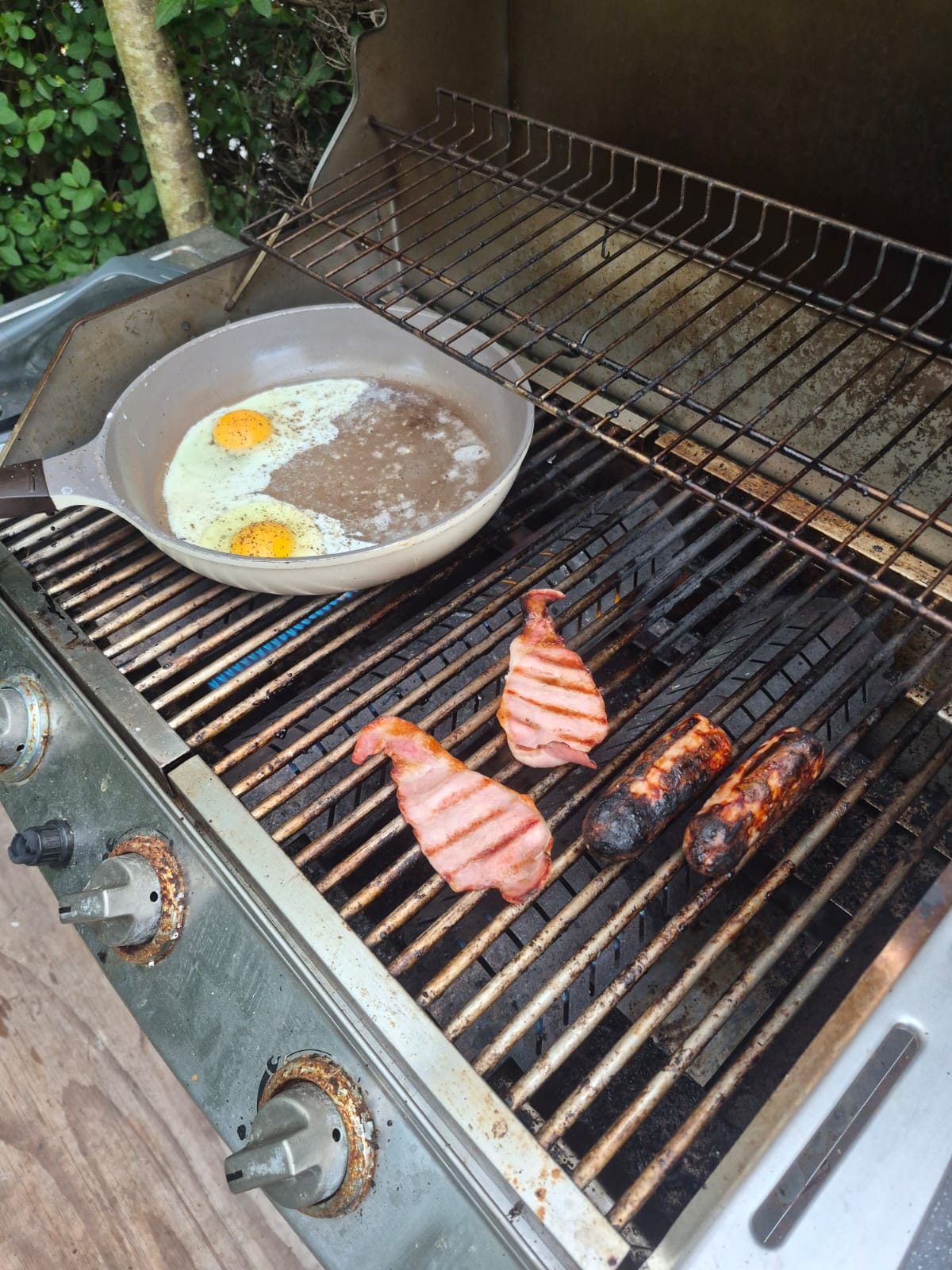 Bacon, sausages and eggs cooking on the grill